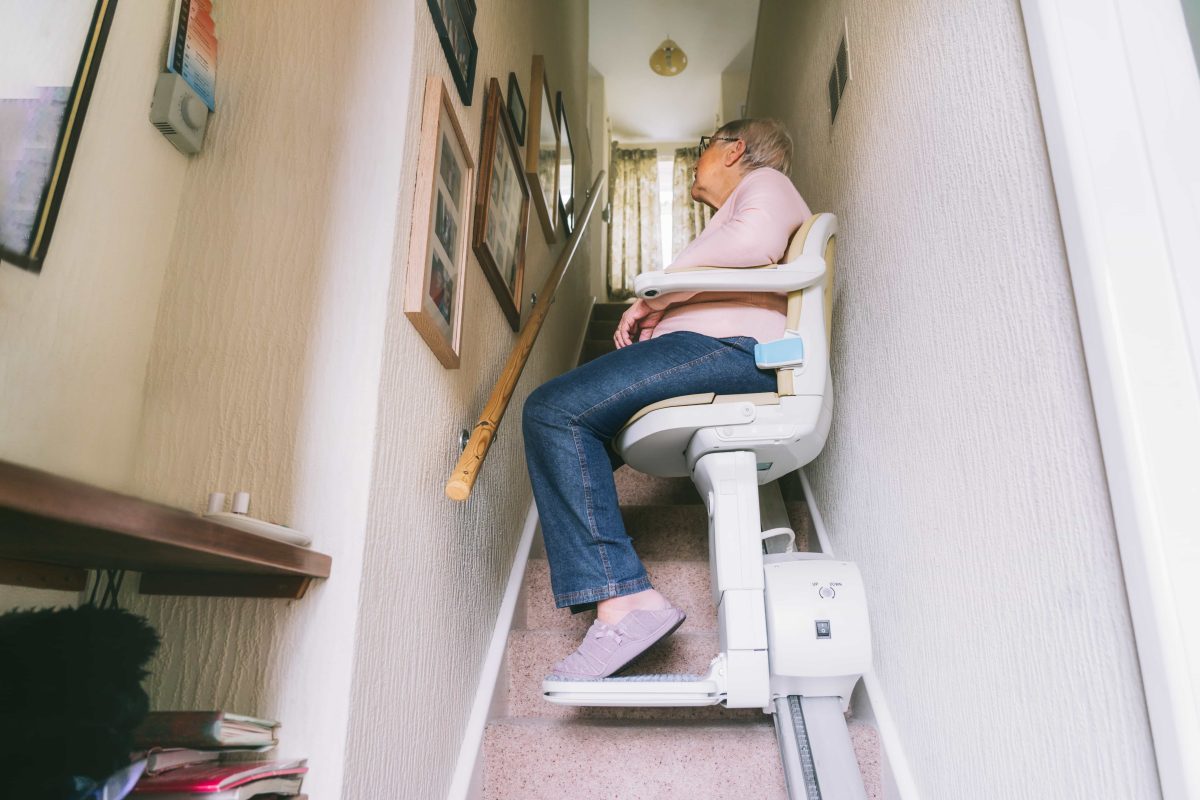 Woman sat on stairlift at bottom of stairs